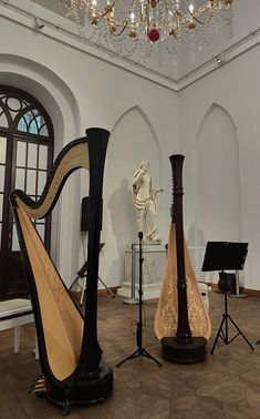 a room filled with musical instruments in front of a statue and chandelier hanging from the ceiling