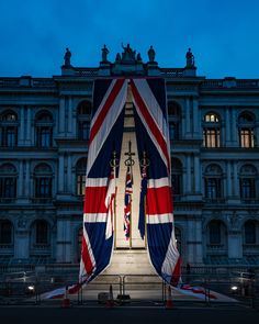 the british flag is being displayed in front of an old building at night with lights on