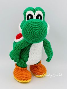a crocheted green frog with orange shoes