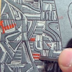 a hand holding a pen over a piece of paper that is drawn with black and red ink