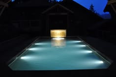 an illuminated pool at night with the lights on and water reflecting off it's surface