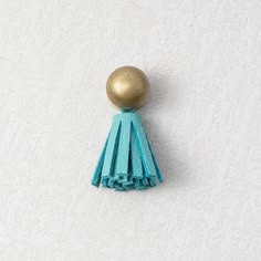 a gold ball and tassel on top of a white wall next to a blue fringe