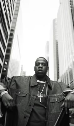 a man standing in the middle of a street with his hands on his hips while wearing a cross necklace