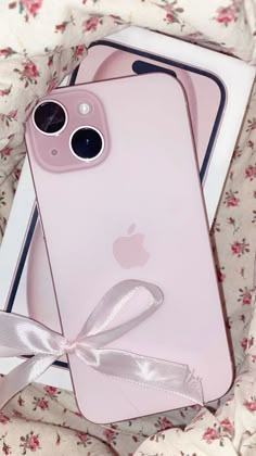 two pink iphones sitting next to each other on top of a flowery blanket