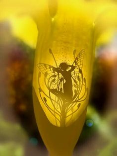 a yellow vase with a silhouette of a fairy holding a flower in it's hand