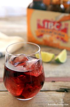 a close up of a wine glass on a table with soda and lemon wedges