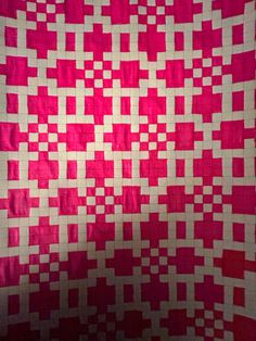 a pink and white quilt with squares on it