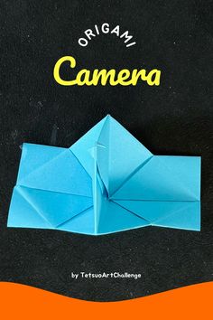 the origami camera is sitting on top of an orange and black surface