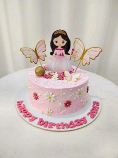 a pink birthday cake decorated with butterflies and a princess figure on top, sitting on a white table