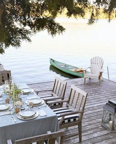 a boat is docked on the water next to a table set with place settings for four