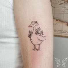 a woman's arm with a tattoo of a duck and flowers on the side