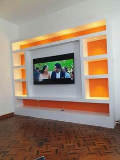 a flat screen tv mounted to the side of a wall in a room with wooden floors