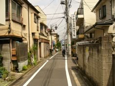 an empty street with people walking down it and buildings on both sides in the background