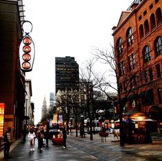 people are walking down the street in front of tall buildings