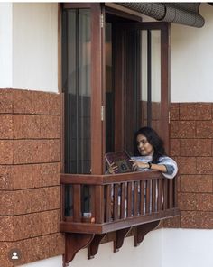 a woman is looking out the window while reading a book in her apartment building's balcony