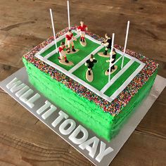 a birthday cake that is shaped like a soccer field with people on it and candles in the middle
