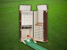 an open suitcase sitting on top of a lush green field next to a cardboard cutout