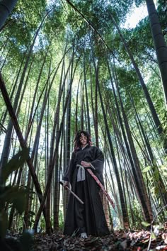a woman dressed as darth vader standing in the middle of a bamboo forest