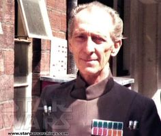 an older man in star wars uniform standing next to a brick building and looking at the camera