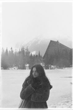 a black and white photo of a woman standing in the snow