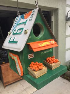 a green bird house with oranges on the outside