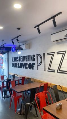 an empty restaurant with tables and chairs in front of a wall that says always delivering our love of pizza