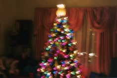 a brightly lit christmas tree in front of a window