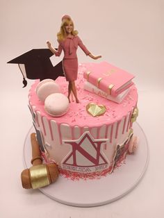 there is a cake that has a barbie doll on it and graduation decorations around it