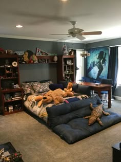 there are stuffed animals on the bed in this living room with bookshelves and shelves