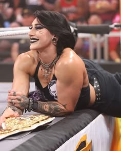 a woman with black makeup and piercings on her face laying down next to a plate of food