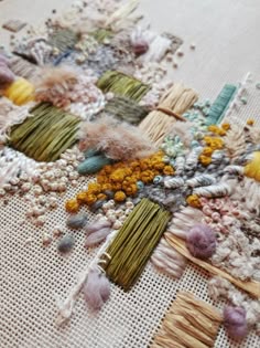 an assortment of yarns and needles laid out on a piece of cloth with different colors