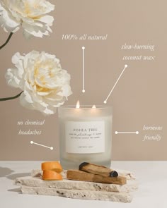 a candle with labels on it sitting next to some flowers and other things around it