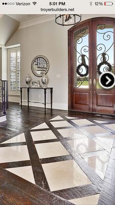a large foyer with wooden doors and tile flooring on the ground, in front of an entry door
