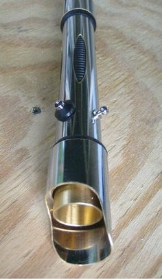 a close up of a metal object on a wooden table with holes in the surface