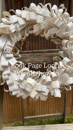 a book page wreath hanging from a wooden fence with the words, book page loops attached to it