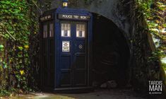 a blue phone booth sitting in the middle of a tunnel with ivy growing around it