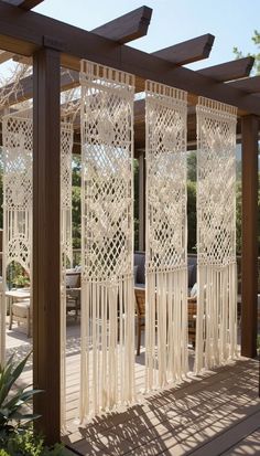 an outdoor area with wooden pergols and white curtains on the side of it