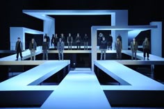 a group of people standing on top of a stage in front of an audience at a fashion show