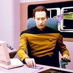 a man sitting at a desk in front of a laptop computer with a star trek character on the screen