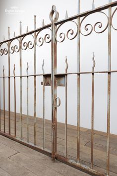 an old iron gate with wooden flooring and white wall in the backround