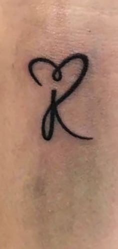 a small tattoo on the back of a woman's shoulder with an initial letter k