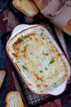 a casserole dish with cheese and bread on the side