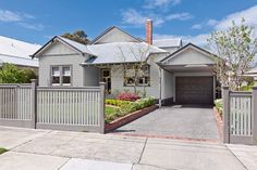 a grey house with a white picket fence