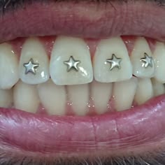 a man's smile with three silver stars on the front and back of his teeth