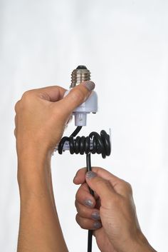 a person is holding an object in their hands while they are working on the light bulb