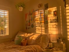 a bedroom with sunlight shining through the windows and decor on the wall behind the bed