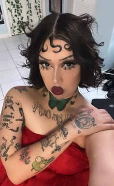 a woman with tattoos on her face and chest is posing for the camera in a red dress