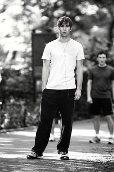 black and white photograph of two young men walking down the street, one with headphones in his ears