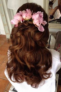 the back of a woman's head with flowers in her hair, sitting on a tile floor