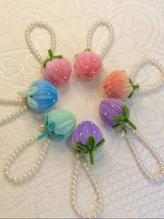 four flower hair clips with pearls and beads on a white tablecloth, one is pink, the other is blue